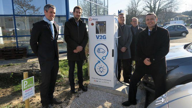 Groupe de personnes devant une borne de charge électrique